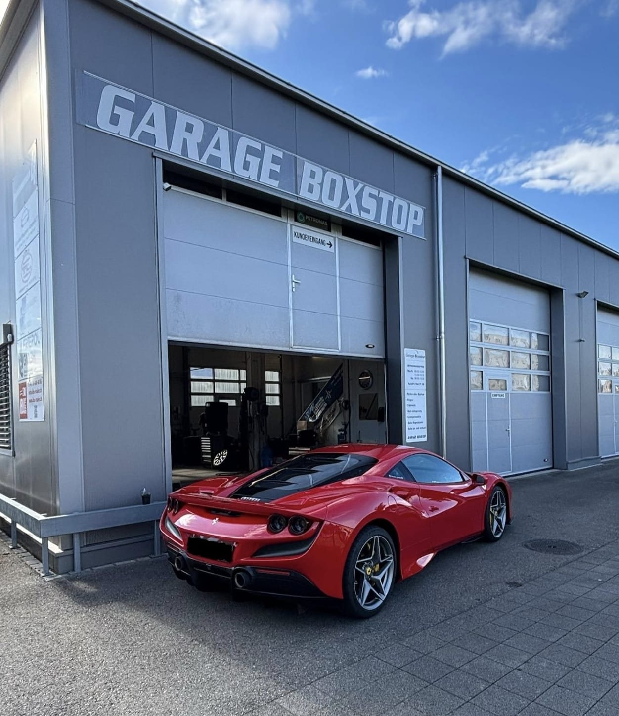 Die Garage Boxstop in Au SG von aussen, mit Sportwagen vor dem offenen Werkstatttor